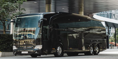 Ein schwarzer Luxus Reisebus vor einem Hotel.