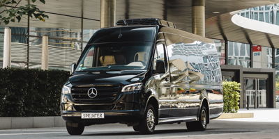 ein schwarze VIP Sprinterbus von Mercedes Benz mit großer Klimaanlage auf dem Fahrzeugdach.